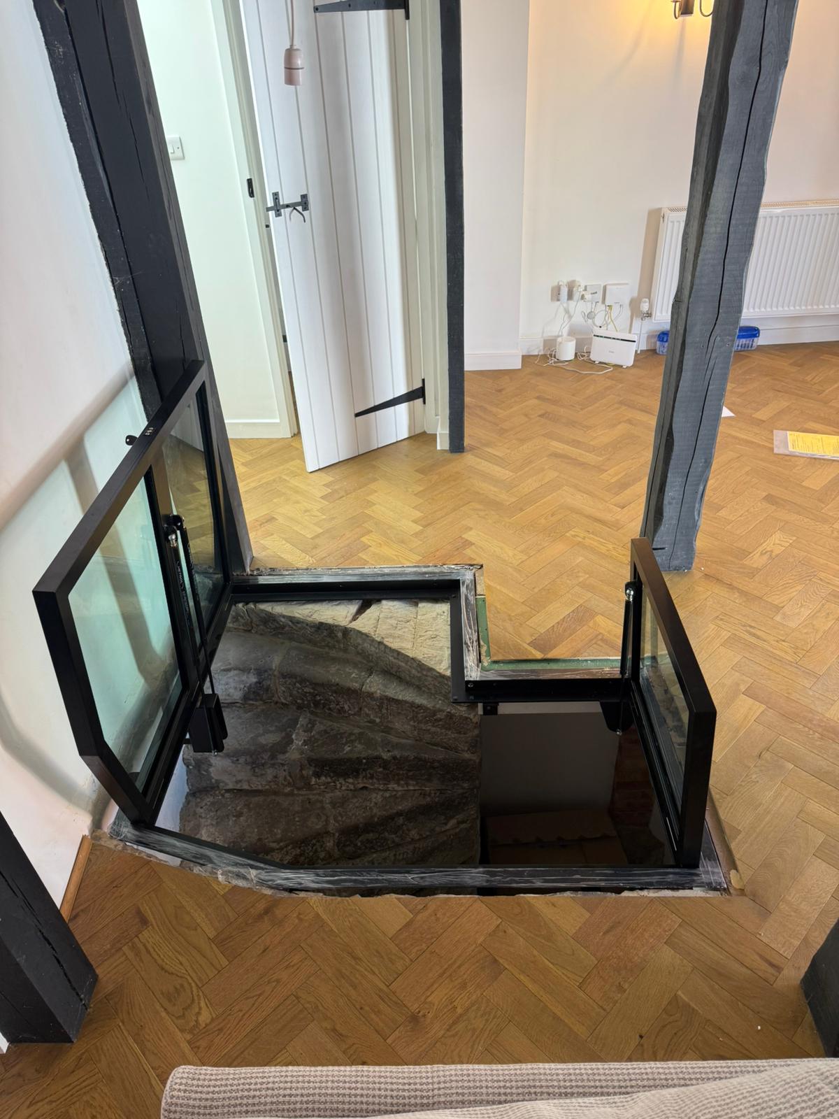 Both hinged glass floor doors fully open, L-shaped opening, stone stairs, exposed timber beams, Burwash period property